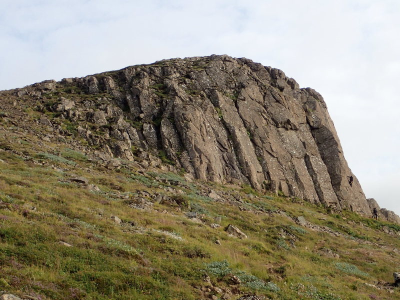 Valshamar climbing crag, as seen from the approach after using the ladder to cross the fence. Climbs are numbered starting from this near side on the approach and increase the further south you go along the face. None of the routes top-out at the top of the cliff band, so do not expect to be able to walk around and hang a rope from the top on any given route. You'd have to build an anchor at the top and rap down to the bolted anchor...