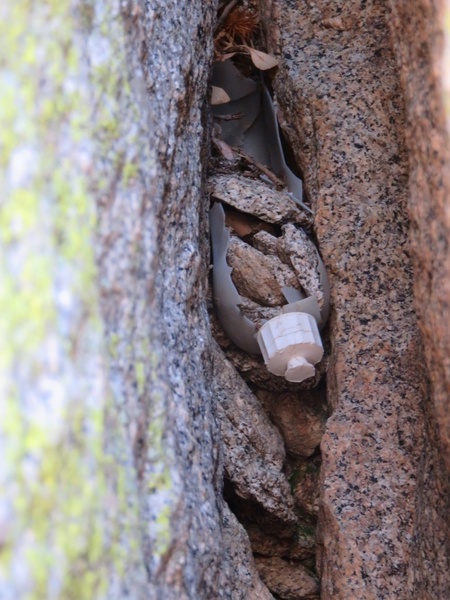 Salad bottle on Pitch 2. Legend has it a member of the second-ascent party, while following, lodged his knee in the wide crack and could not get it out. His partner rappelled and ran to the nearby fire lookout, got a squeeze bottle of salad oil from the tower attendant, and used this to help free his partner's knee. The bottle remains wedged in the offwidth to this day.
