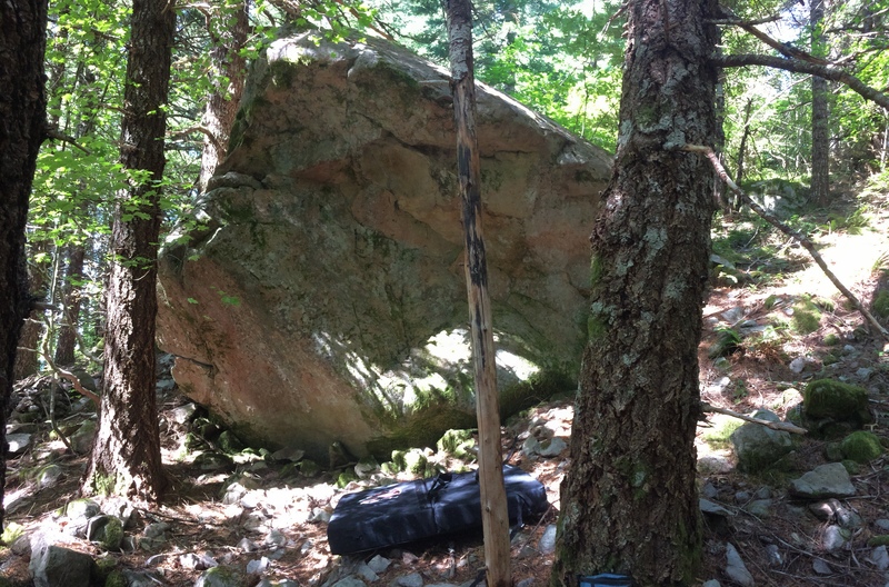 50-100 yards in from the field. Toward the top of the hill. Traverse and exit left for an easy climb (V0) or pull over the bulge for a more difficult problem (V3?). Spotter recommended.