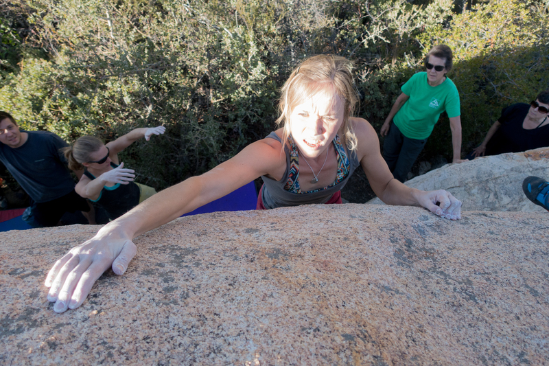 Sanni looks for the handhold at the top of Two Holds with the sun in her face.