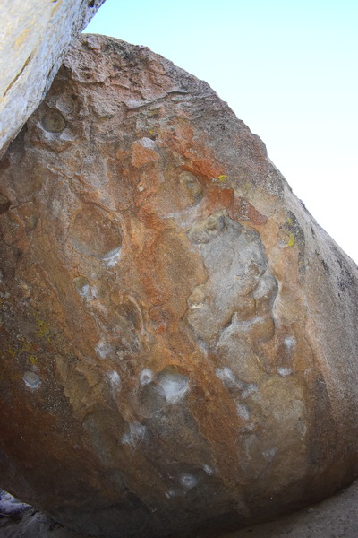 The overhang of the boulder.