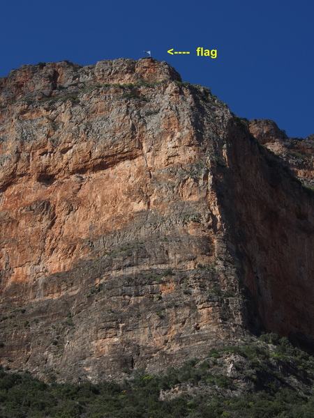 Greek Flag flys above the Douvari section (grey rock) of Kokkinovrachos