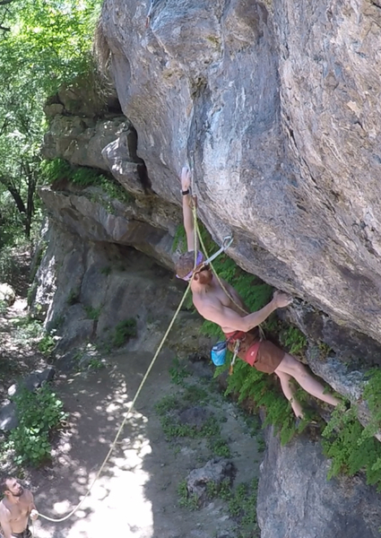 Beginning the opening boulder problem on the route. Left hand is in the first drilled pocket and right hand is on starting jugs