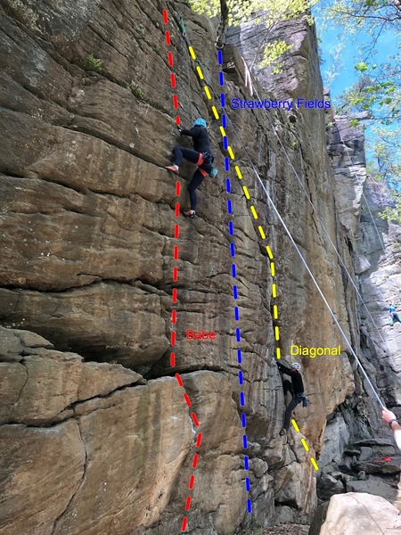 Rachel halfway up Babe (red) while another climber starts Diagonal (yellow) with Strawberry Fields (blue) in between them.
