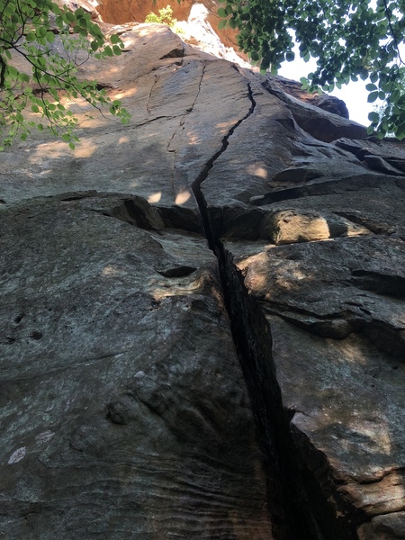 Wide crack tapers to tight hands before the small ledge, step left & pull onto slab w/ finger crack (right side of the small arete in top of pic).