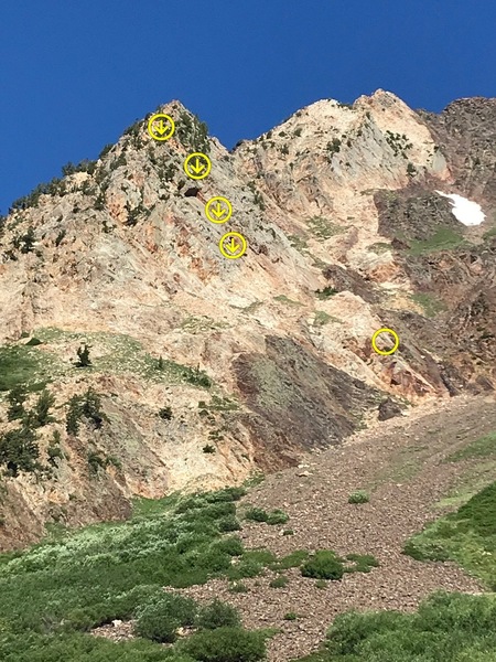 Suicide Slab starts on the sliver of light colored rock at the top of the talus below the snow patch. The route climbs up to the ridge in the trees just down from the point.
