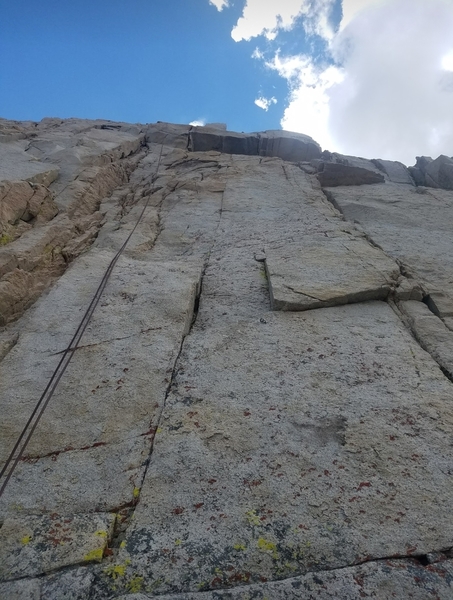 Looking up at pitch 3, route follows bolt line on face to right of rope.