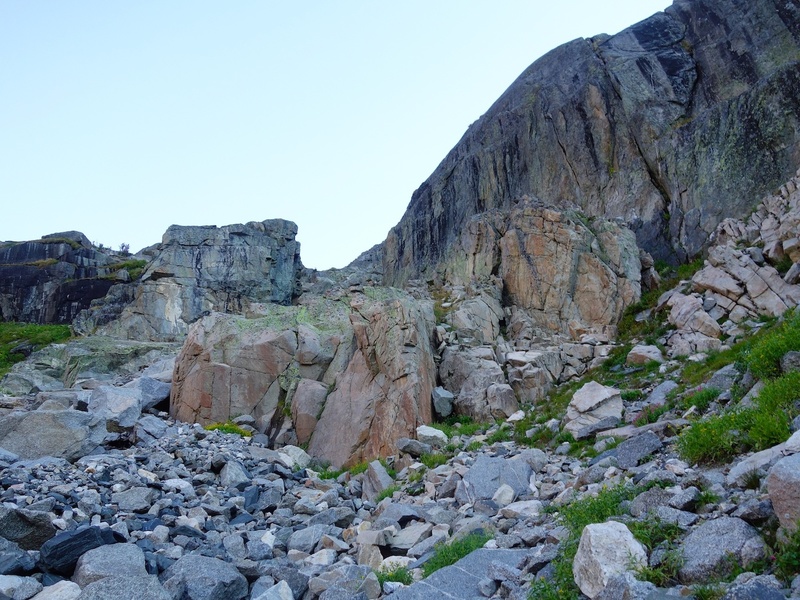 Skirt left below rock walls until you come to the giant square-shaped slot (the "Garage Door"). Then cut right up the grassy/rocky slopes to the base of the route.