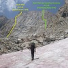 Steve approaches the massive east face of Humphreys in mid-summer conditions. Yellow and green lines show the known routes on the wall.