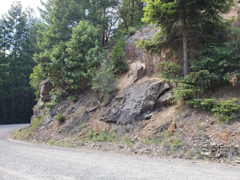 View of the base of the approach trail from the road. Scramble up the hillside and traverse across to the left using the handrails. T-Rex Rock and others will be to the right (east), Stegosaurus Rock will be uphill.