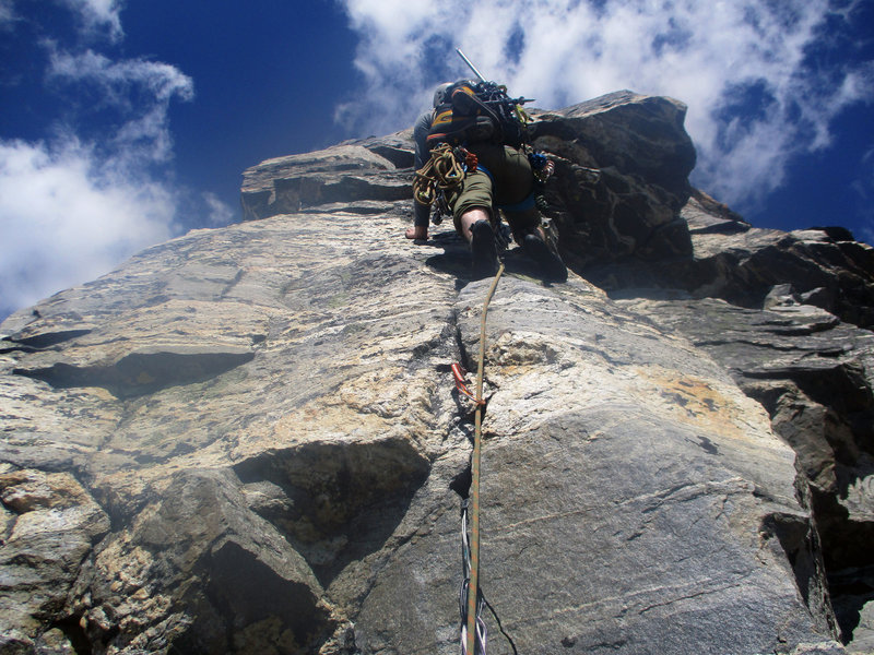Brock leading up the first section of the third pitch of our off-route variation. From here he traversed hard left around the corner and up steep blocks before regaining the ridge crest above the roof.