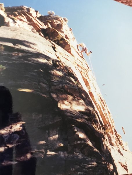 Tyler Phillips on cleaning loose rock on lead during FA of Gratitude. Early Bird Gets the Worm follows the crack in the shadow at the bottom of the photo up to the splitter in the sun and then the dihedrals to the shrub on the summit.