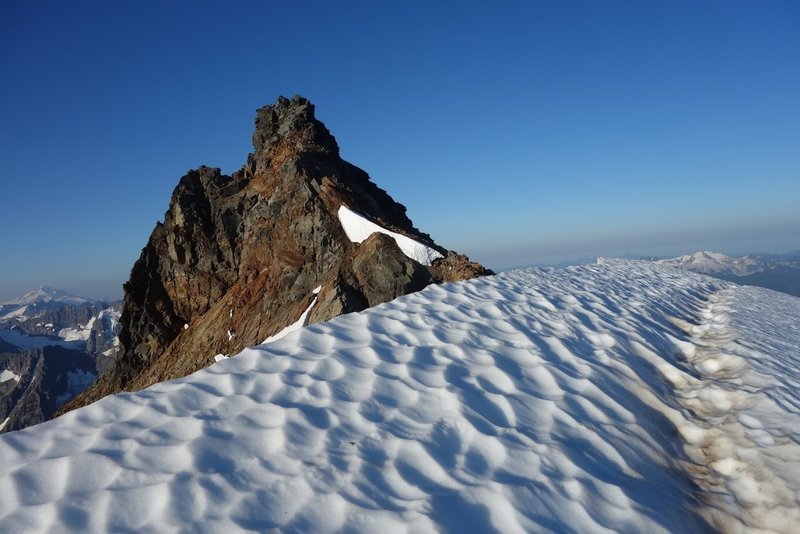 The final snow traverse and rock summit of Sahale in 8/2019. The rock ahead had a few moves of low 5th class that was readily down-climbable. (Photo: Mark F.)