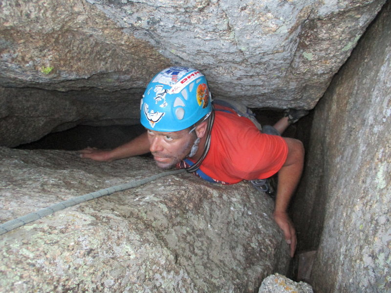 Dirk making the final moves of the climb after tunneling behind the giant chockstone.