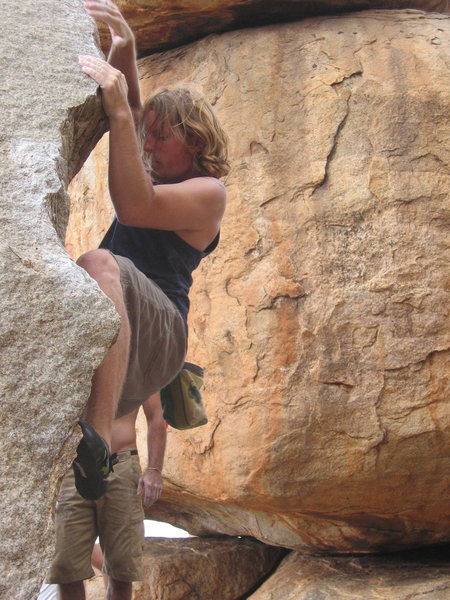 Travis Eiselstien gripping the slopers on Arete on the Cosmic Friction Boulder in Hampi, India.