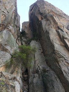 The whole route as seen from the ground, taking the left-facing corner to the final step beneath the top of the pinnacle.