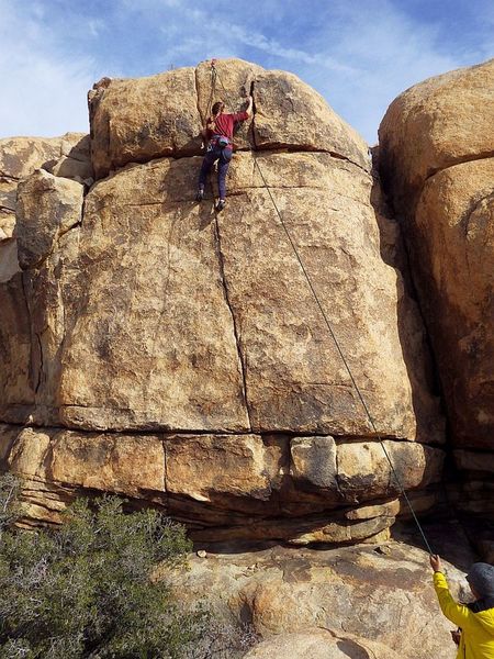 Nicole near the top of Ancestral Puebloans. The left-slanting dihedral crack to her right is The Sound of One Hoof Knocking. Ancient Ones just out of frame off to the left. Dec 2019.