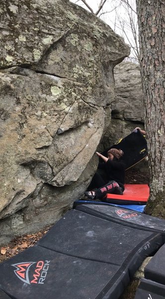 Climber at the starting jug. A slide pad is used to protect the climber. A tree is also very close.
