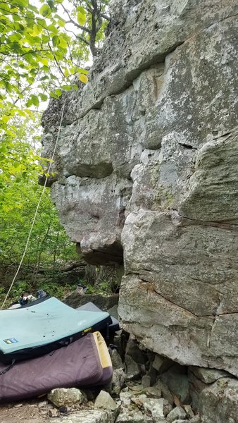 Move from just right of the roof into the face over the roof and topout directly above. Bring several pads as the landing is a floor of talus.