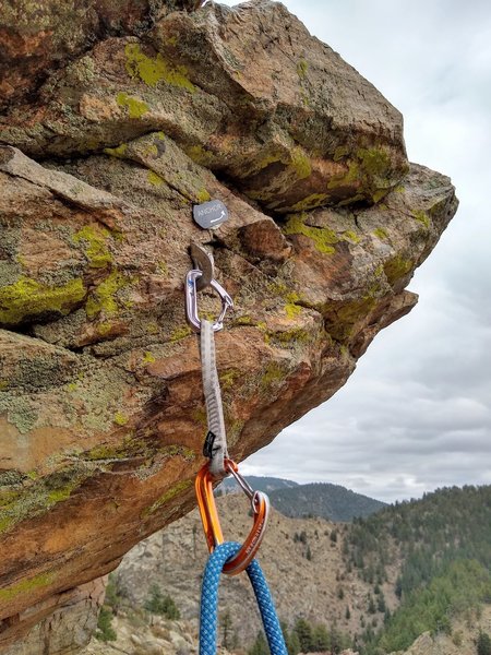 The anchor placard points to a trad anchor above for belaying follower from top. Use the rappel anchors to climber's left for rappel.
