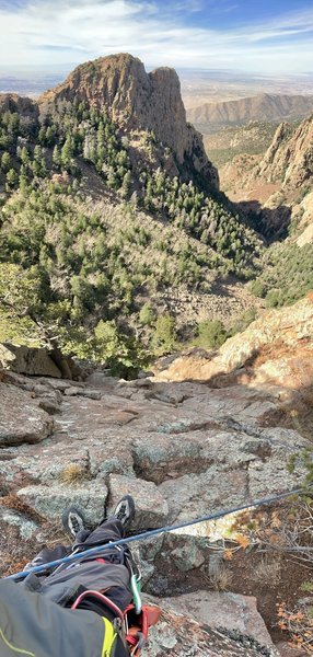 The tree below and center (where rope disappears) is just above the chicken head on P2. Instead of following my rope up the face, where loose blocks abound, trend climber's left up the grassy ramp in the sun toward the much preferred red rock corner.