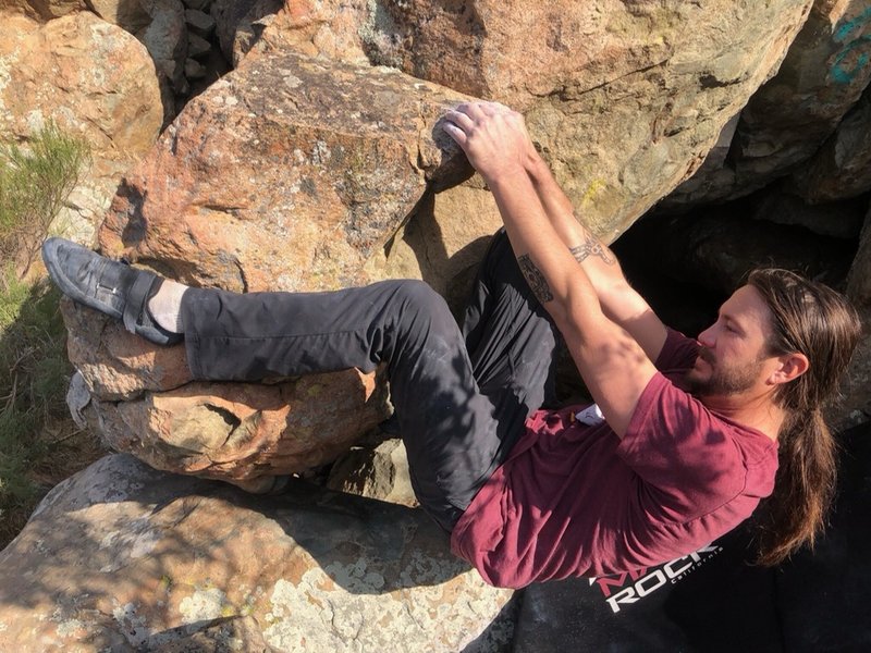 Starting position, lower left side of boulder with both hands on big ledge jug, and left heel on side of boulder. Right foot is placed on a hold below hands.
