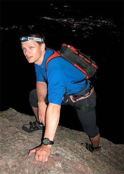 John reaches the summit on a moonlight ascent with the lights of Boulder behind.