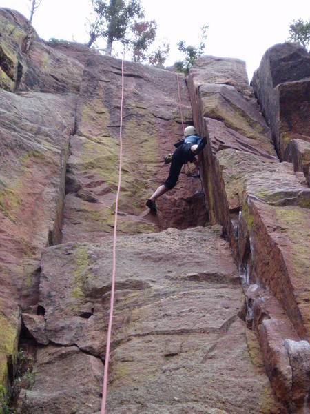 Wide stemming on the second half. There is a hard move up high that you can bypass by moving right onto the arete for one move.