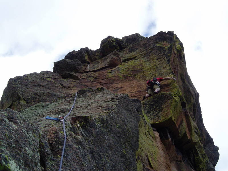 At the arete, if you're tall enough, you can maneuver your feet and reach up to a one joint finger hold. Then traverse left back to the 3rd bolt along the slightly rising thin horizontal crack. If you're too short, the move at the arete must be pretty hard. In any case, a fall from here would be ugly, since the bolt is about 10' to the left.
