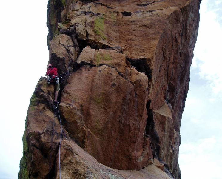 Luke at the P1 crux. This is quite hard, maybe 9+. Luke has his leg hooked around the corner for a rest.