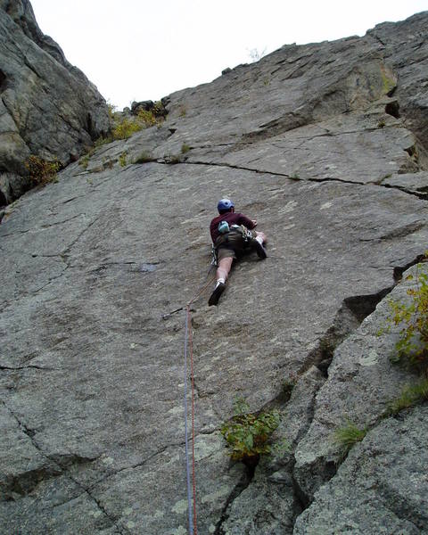 This high step didn't work for Paul. If you're tall enough (he isn't) you can reach a good edge with your left hand and crank onto the good foothold in the crack, thus avoiding any thin feet. But it's still very thin moving right from there to the other crack. That's how I did it the first time, but I now think it's easier to do the thin foot moves and make a less extreme step up.