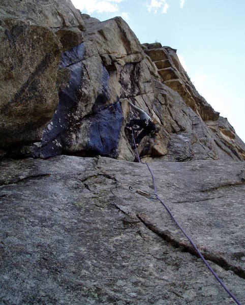 Stepping left onto the steep headwall at the start of P3. It rained a lot the previous 2 days, hence the major wet streaks to Chuck's left. The climb diagonals right acoss the black streaks up and left from Chuck and then moves left onto the arete at the top center of the photo.<br>
<br>
Photo by Ivan Rezucha.