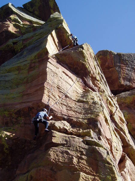 An easy hand traverse with good gear leads to a stance to the right of Chuck. There's a hard move to reach the finger crack by Chuck's left knee. John Courtney is belaying.