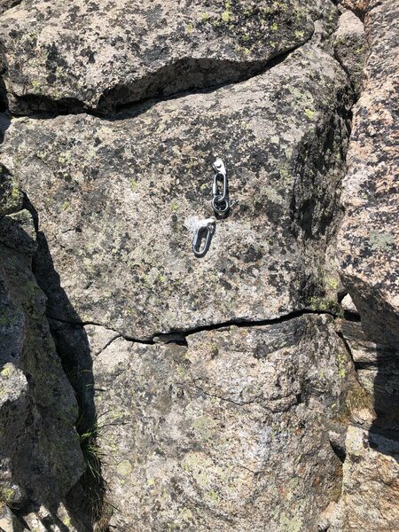 The summit rappel rings, which are a short downclimb from the summit in an alcove.
