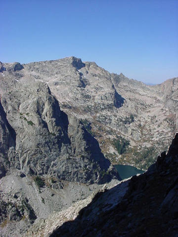 From the west side of Shoshone Peak: The North Face route diagonals left across the tree-covered bench into the shadowy cleft splitting the face.