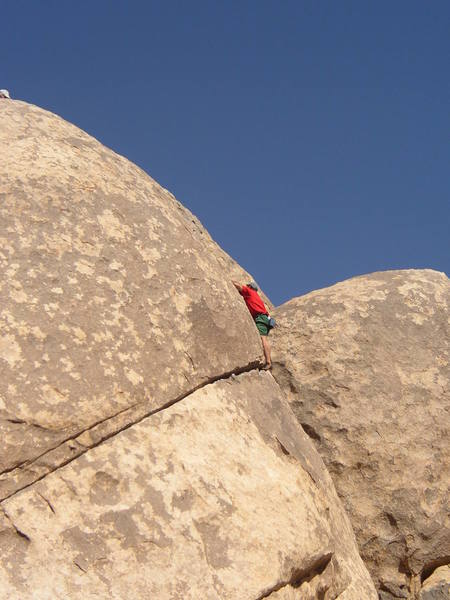 East Coast Larry on the last section of the route. He is stretching for a hold,not wanting to leave his crack... A very fun climb. Can be top-roped. There are two bolts at the top (where the white hat is in the picture, upper right side...)