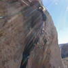 Christa Cline starting the second pitch traverse into a bright afternoon sun.