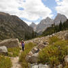 Hiker descending Upper Cascade Canyon with Grand Teton in the background.