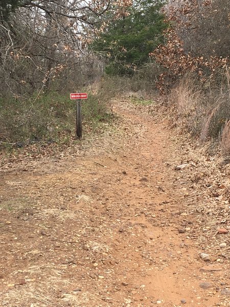 While this sign may be confusing, it is perfectly legal and recommended for foot traffic to start the trail at this spot. Mountain bike traffic is routed the opposite direction in order to prevent user conflict.