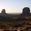 Two buttes at Monument Valley cast shadows over the land in the early morning light.