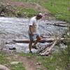 An adventurer builds and tests a log bridge to cross Little Cimarron River during spring flooding.