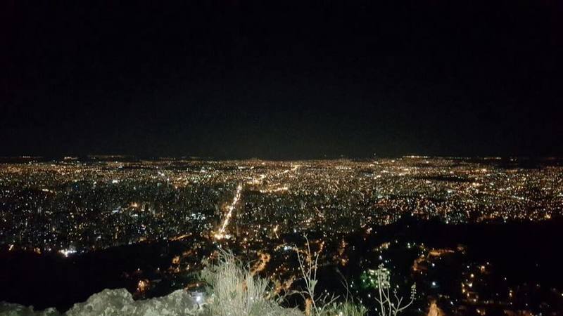 The city shines from the summit at night.