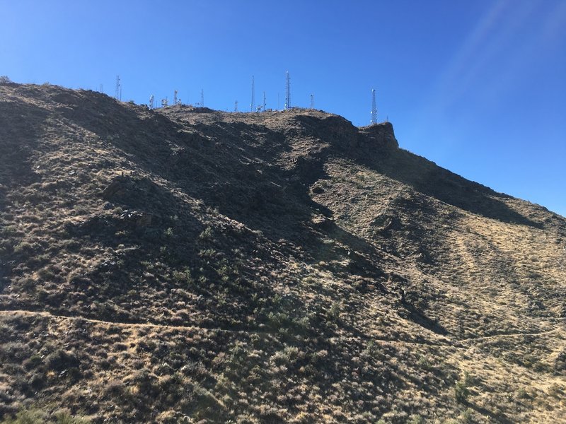 A Mountain with radio towers sits above the trail