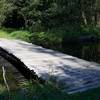 A wooden bridge crosses a stream that feeds into Shell Pond.
