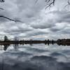 Cloudy skies reflected on a still lake.
