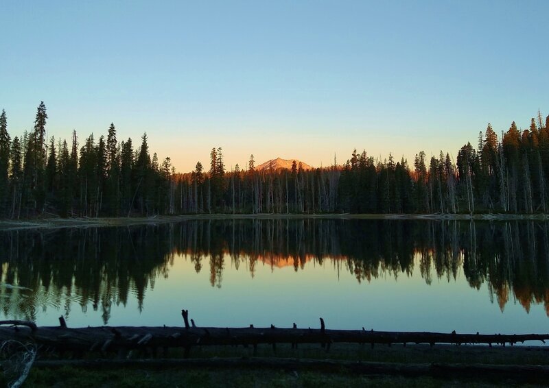 Mt. Lassen catching the first light of dawn and reflecting into Rainbow Lake.