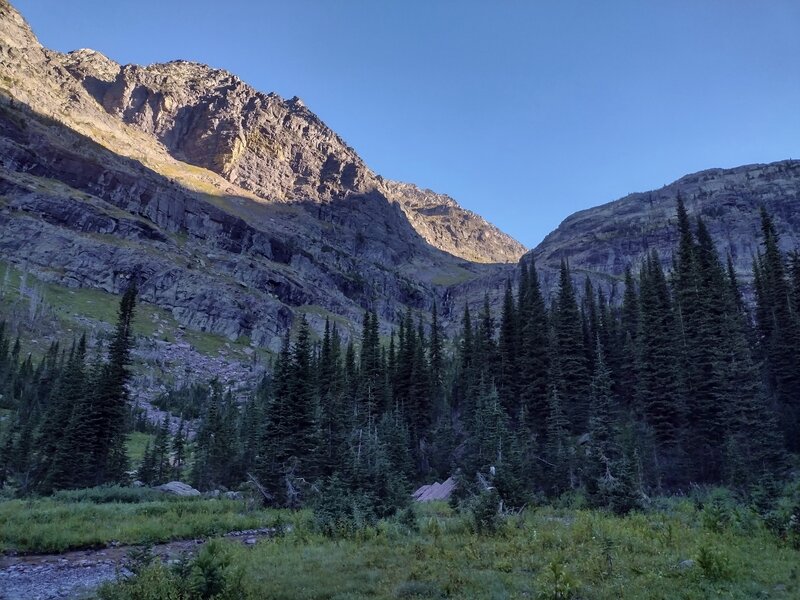 Headwaters of Sprague Creek are seen cascading down from Sperry Glacier - center right, and running through this meadow, lower left.  Sunlit Edward Mountain (left) and Lincoln Peak ridges (right) are walls of the gap that the creek cascades down from.