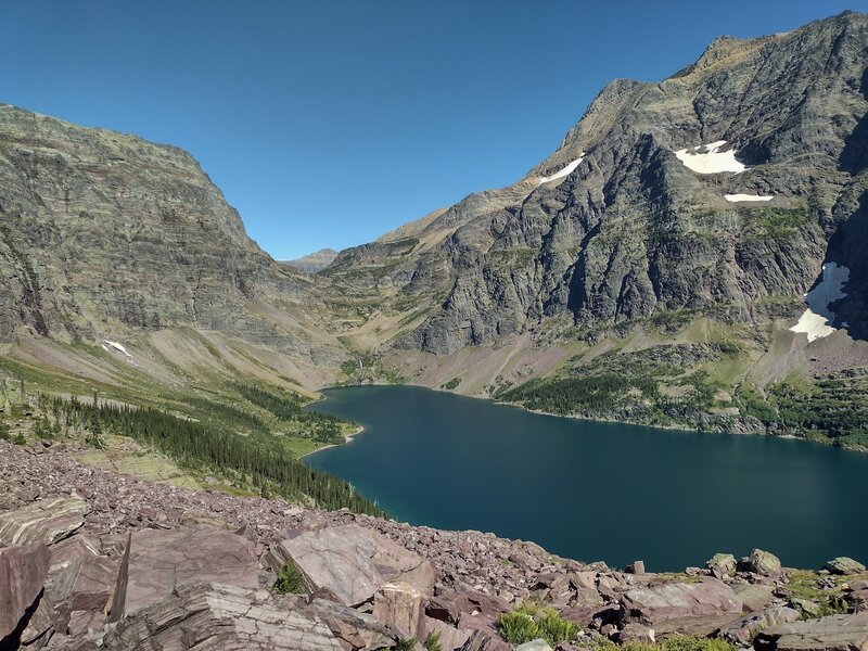 Lake Ellen Wilson below. The trail comes through Gunsight Pass (center left). Gunsight Mountain is northwest/left of the pass.  Mount Jackson is southeast/right of the pass. All on Continental Divide. Citadel Mountain far distance on other side of pass.