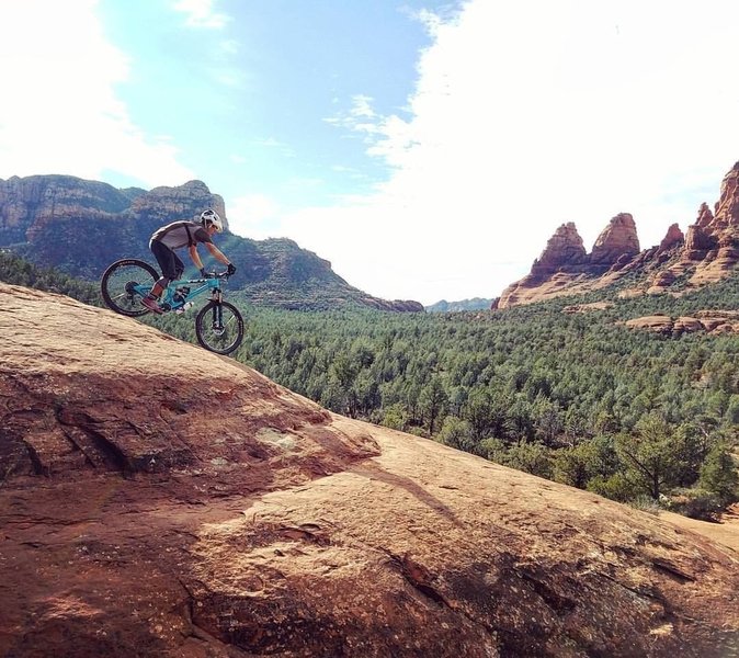 A rider rolls down Submarine Rock to gorgeous views of Twin Buttes.